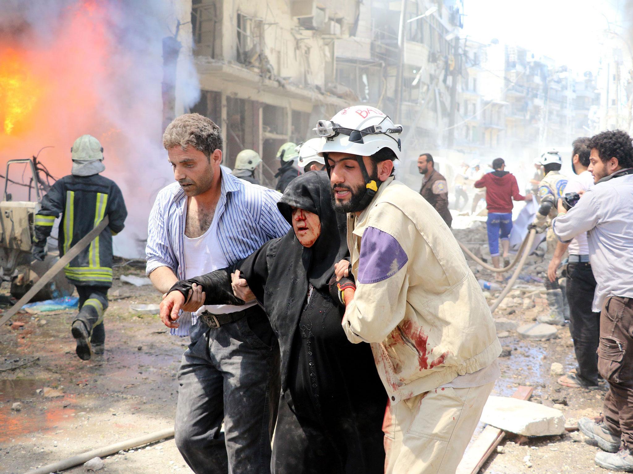 Syrians help a wounded woman after suspected barrel bomb attacks on Beyan hospital and a bazaar in Aleppo, Syria on 8 June, 2016