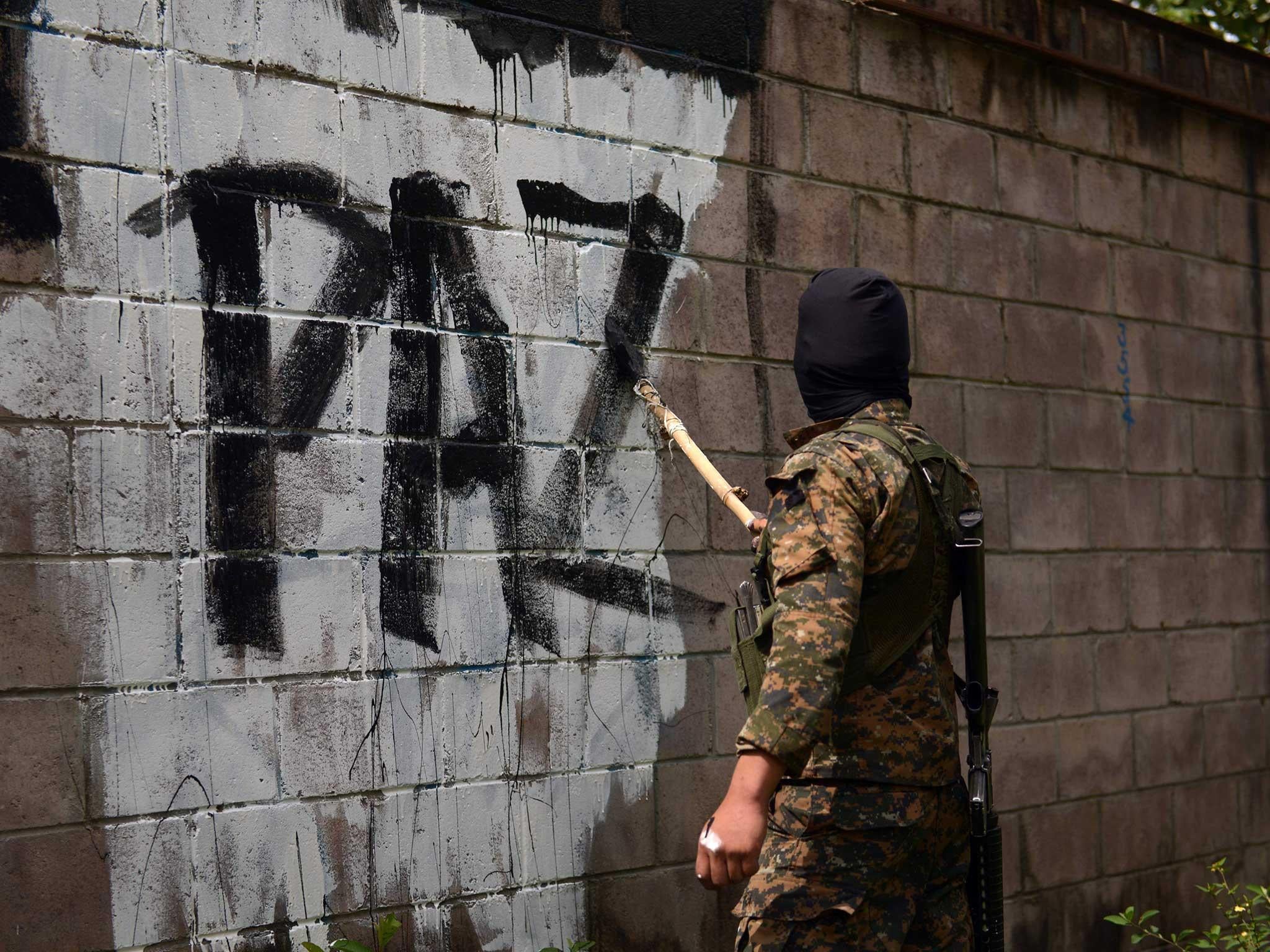 A soldier paints over graffiti associated with the Mara Salvatrucha gang in Quezaltepeque, a town 15 km from San Salvador, in an operation to take back gang-controlled neighborhoods