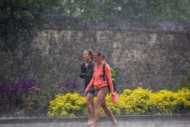 Two women walk barefoot through heavy rain in Westminster in London. The Met Office has issued flood alerts for parts of the south east of England as torrential rain hit parts of the country