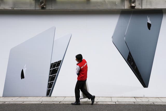 A staff member of Japanese electronic retailer Bic Camera walks past an advertising poster of Apple MacBook laptops in Tokyo, August 25, 2015