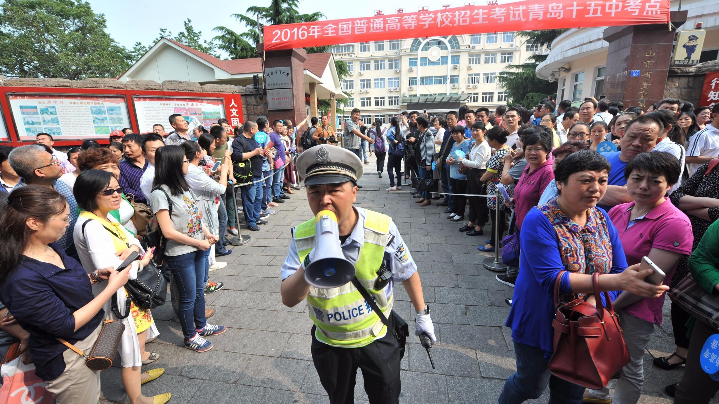 A policeman clears a path for students outside a university gaokao entrance exam in Qingdao, in China’s Shandong province this week