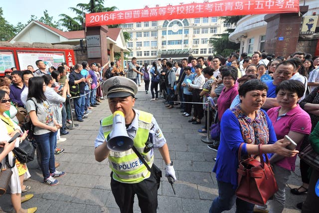 A policeman clears a path for students outside a university gaokao entrance exam in Qingdao, in China’s Shandong province this week