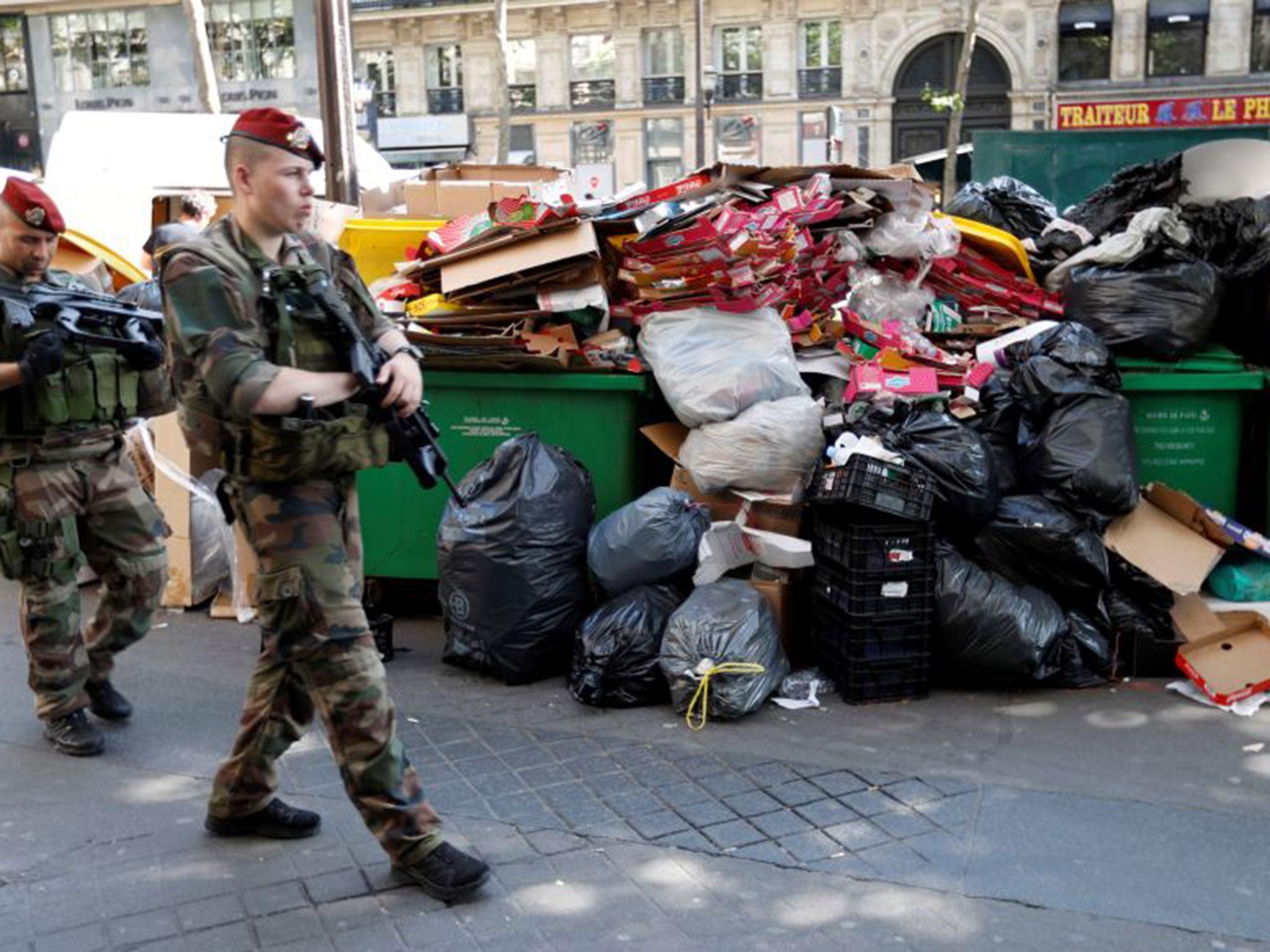 Soldiers pass by a pile of rubbish bags on the Grands boulevards in Paris, France