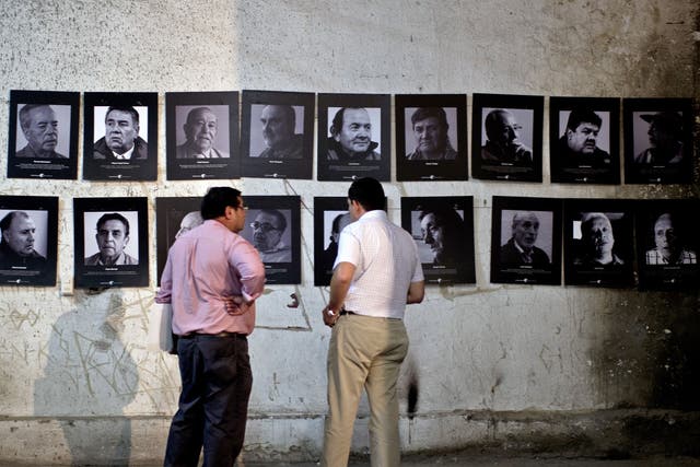 Members of the 'Former Political Prisoners of the National Stadium' stand next to pictures in a room at the National Stadium that served as a jail for prisoners during the killings