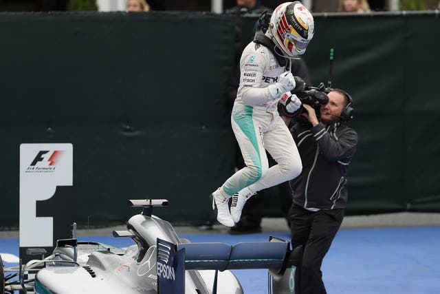 Lewis Hamilton leaps off his Mercedes in celebration after winning in Canada