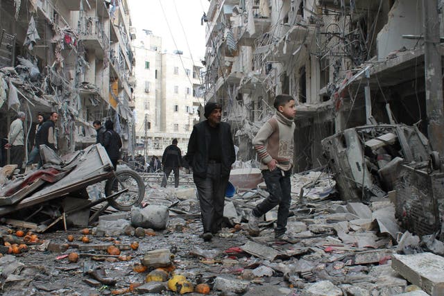 An elderly Syrian man and a child walk amidst debris in a residential block hit by explosives in Aleppo