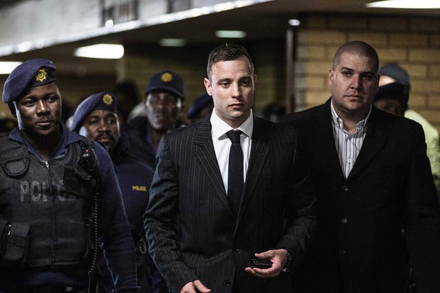 South African Paralympian Oscar Pistorius is surrounded by policemen as he arrives at Pretoria High Court to attend a sentencing hearing set to send him back to jail for murdering his girlfriend Reeva Steenkamp three years ago