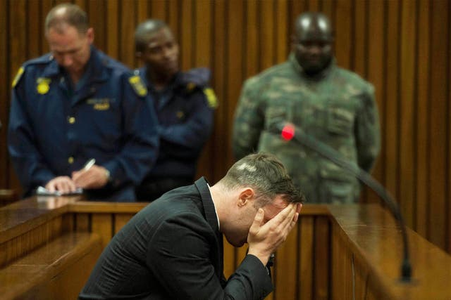 Oscar Pistorius covers his face as the father of his late girlfriend testifies at the Pretoria High Court yesterday