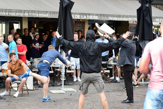 A Russian football supporter lobs a chair towards Slovakian fans sitting in a cafe in Lille