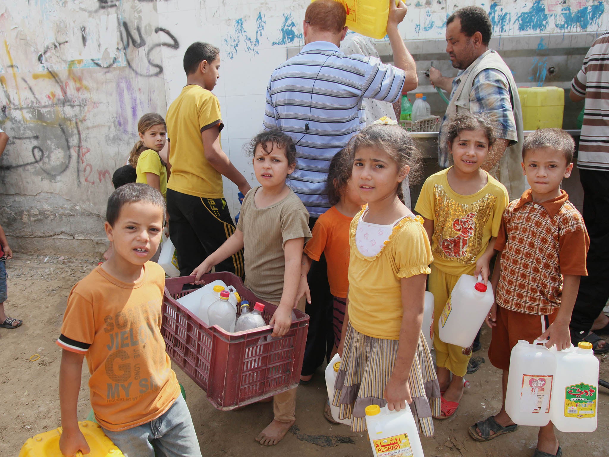 Palestinian children fill bottles with water from a public tap in Khan Younis due to water shortages