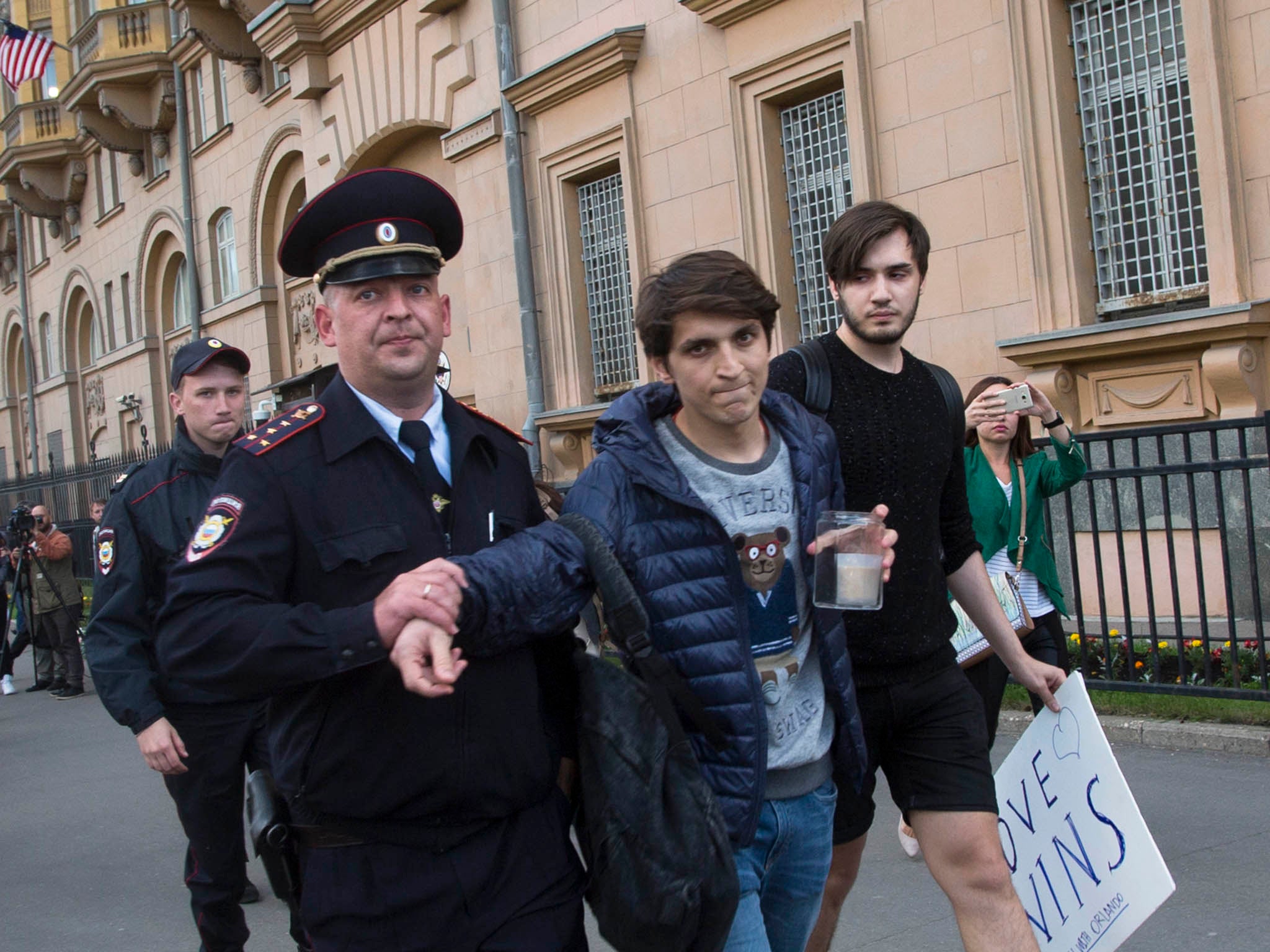 A Russian police officer detains a gay rights activist as he tries to show a poster reading "Love wins" at an impromptu memorial in memory of the victims of the Orlando nightclub attack at the U.S, Embassy in Moscow, Russia, Monday, June 13, 2016