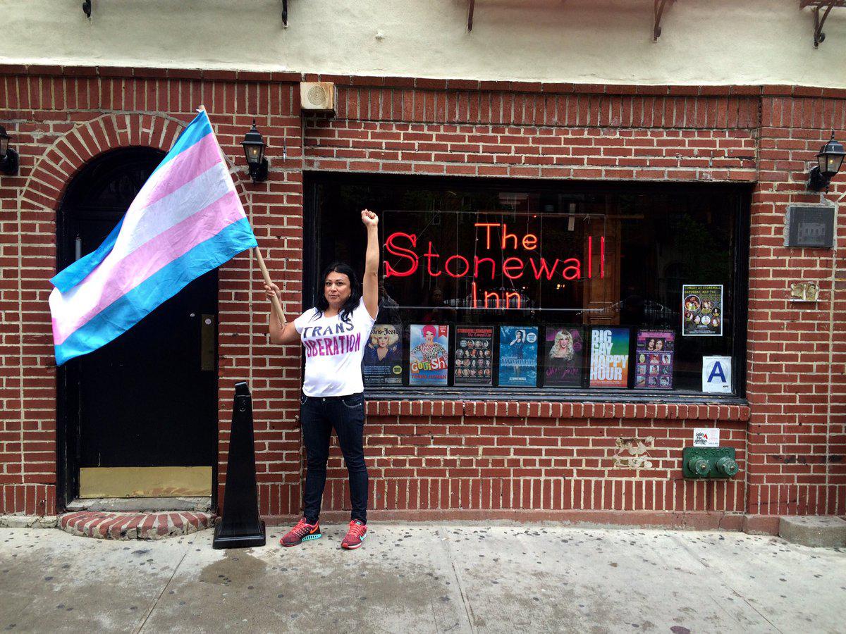 Gutiérrez stands in front of the Stonewall Inn holding the Transgender flag (Jennicet Gutiérrez/Twitter)