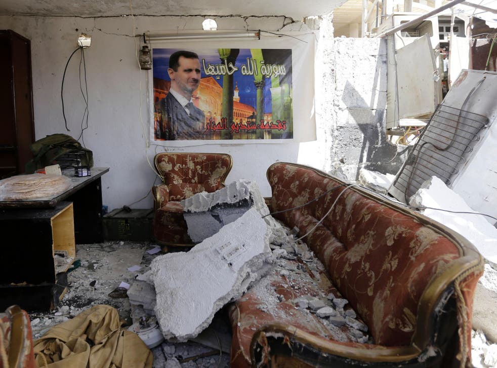 A poster of Syrian president Bashar al-Assad hangs in a Damascus apartment destroyed by car bomb <em>Louai Beshara/Getty</em>