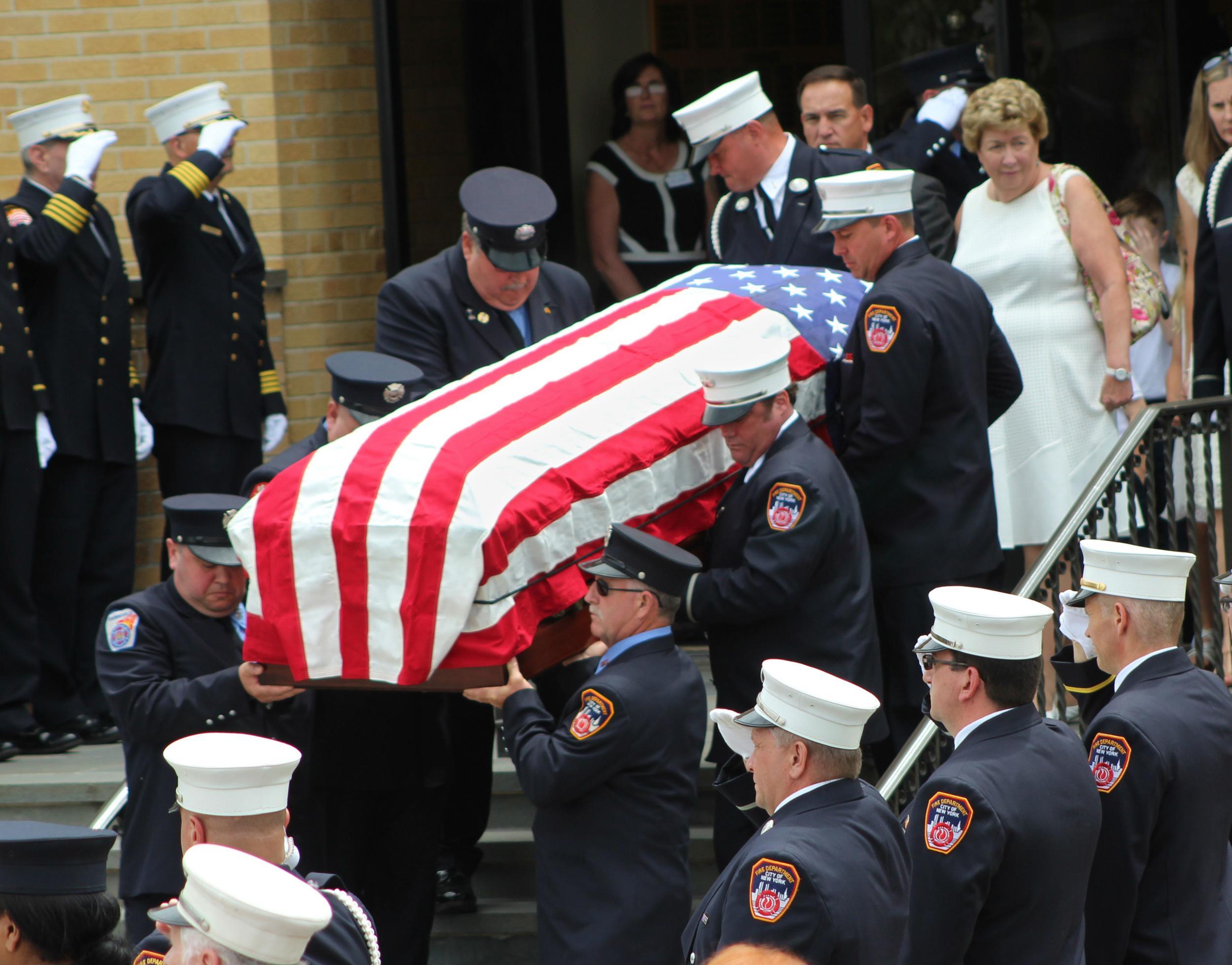 The flag-draped casket is followed by Mr Stack's wife, Theresa