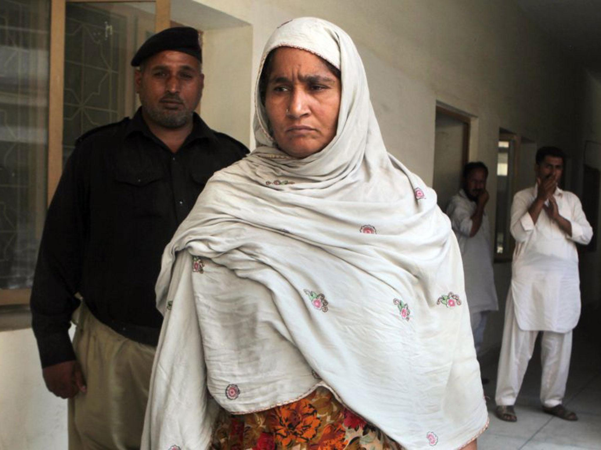 Amina Bibi, center, who who local police say killed her pregnant daughter, 22-year-old Muqadas Tofeeq, is detained at a police station in Gujranwala, Pakistan