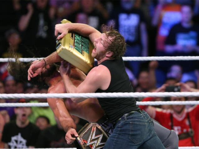 Ambrose smacks Rollins with the briefcase before taking his world heavyweight title