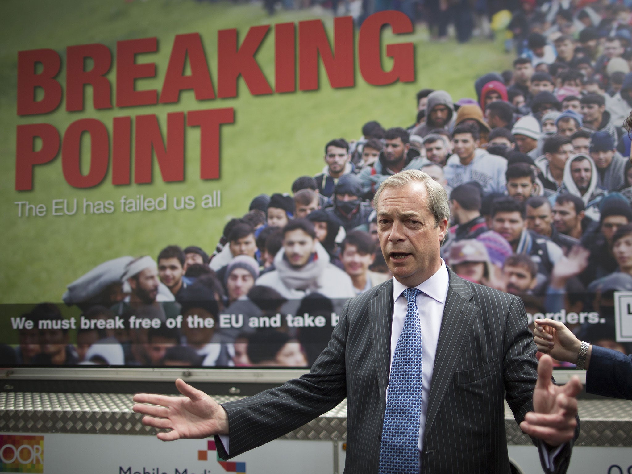 Nigel Farage poses next to his controversial 'Breaking Point' poster