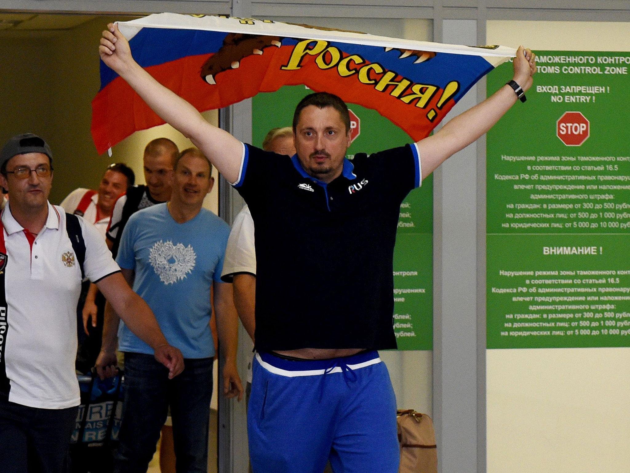 Russia's football fans leader Alexander Shprygin holds a flag as he leaves with others fans the international airport Sheremetevo near Moscow late on 18 June, 2016 after being expelled from France