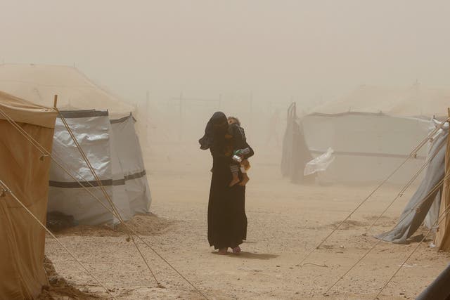 A woman, who fled from Fallujah carries her child during a dust storm at a refugee camp in Amiriyat al Fallujah in Iraq on June 16, 2016