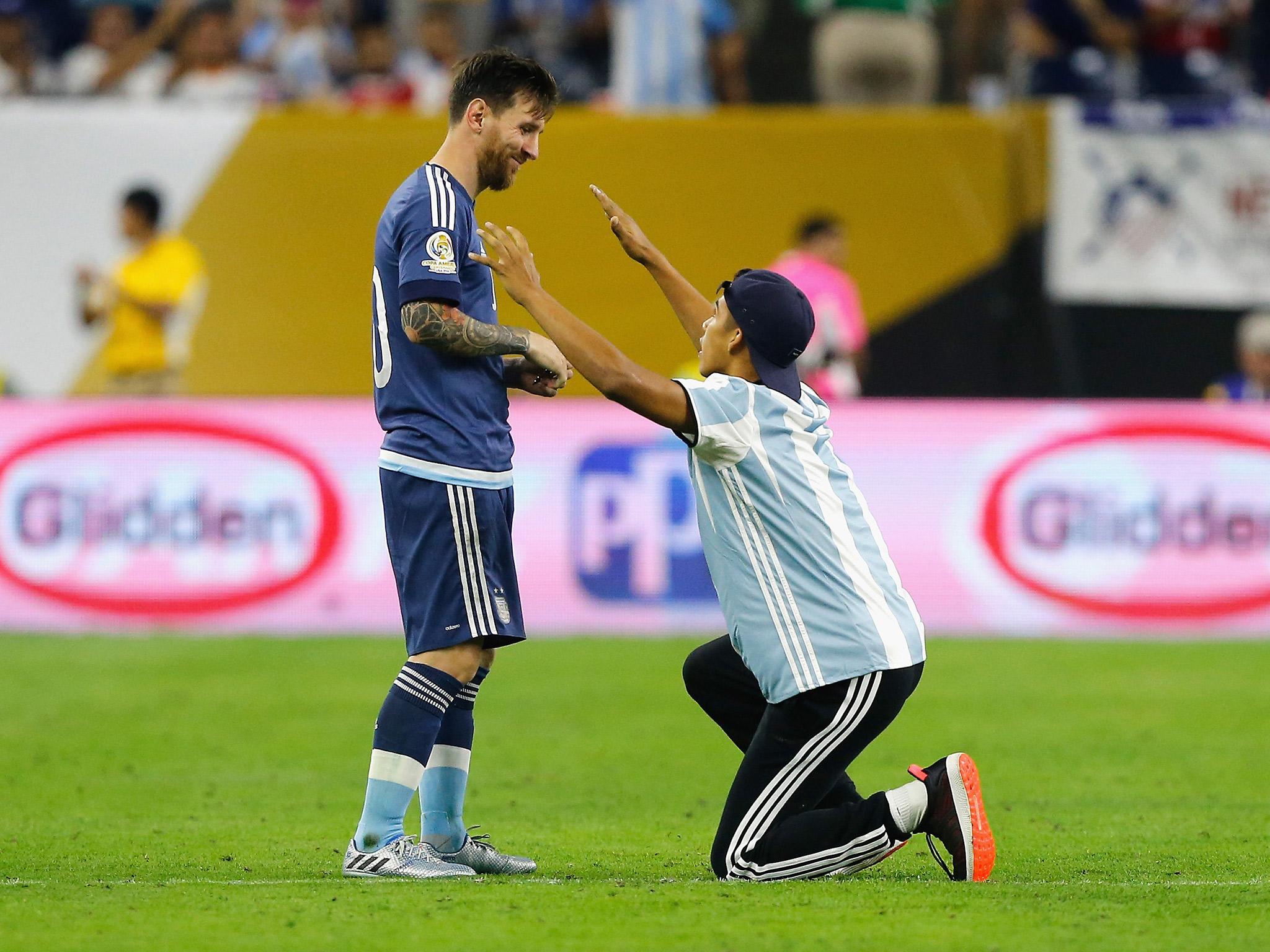 A fan runs onto the pitch to praise Lionel Messi during the win over USA