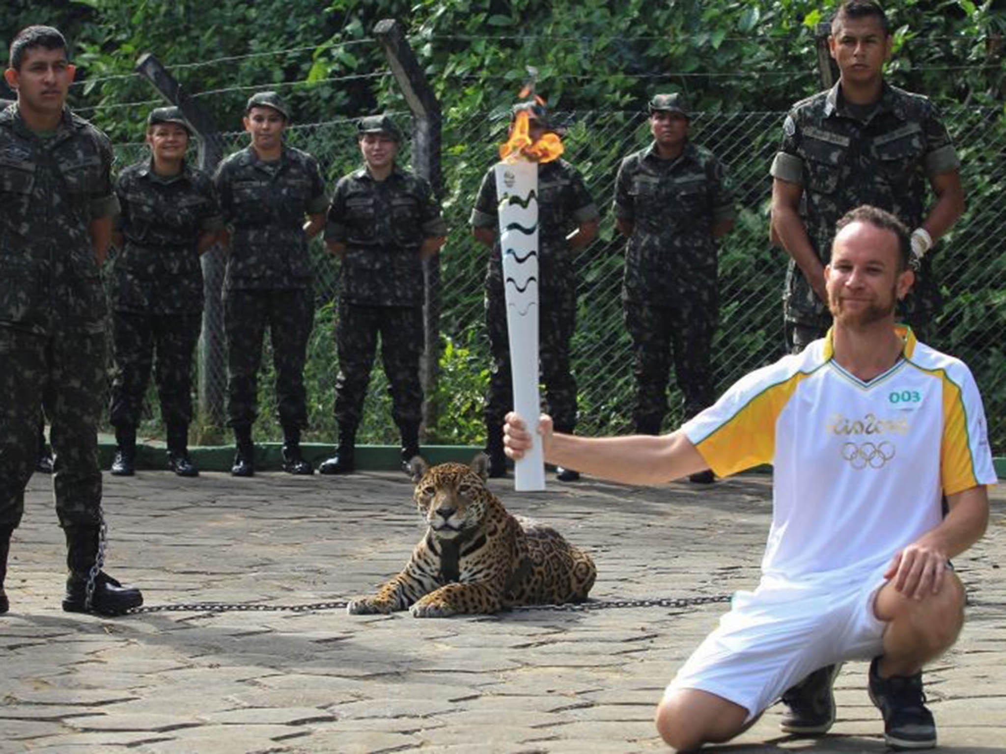 Brazilian physiotherapist Igor Simoes Andrade poses for picture next to jaguar Juma as he takes part in the Olympic Flame torch relay in Manaus, Brazil, June 20, 2016