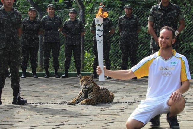 Brazilian physiotherapist Igor Simoes Andrade poses for picture next to jaguar Juma as he takes part in the Olympic Flame torch relay in Manaus, Brazil, June 20, 2016