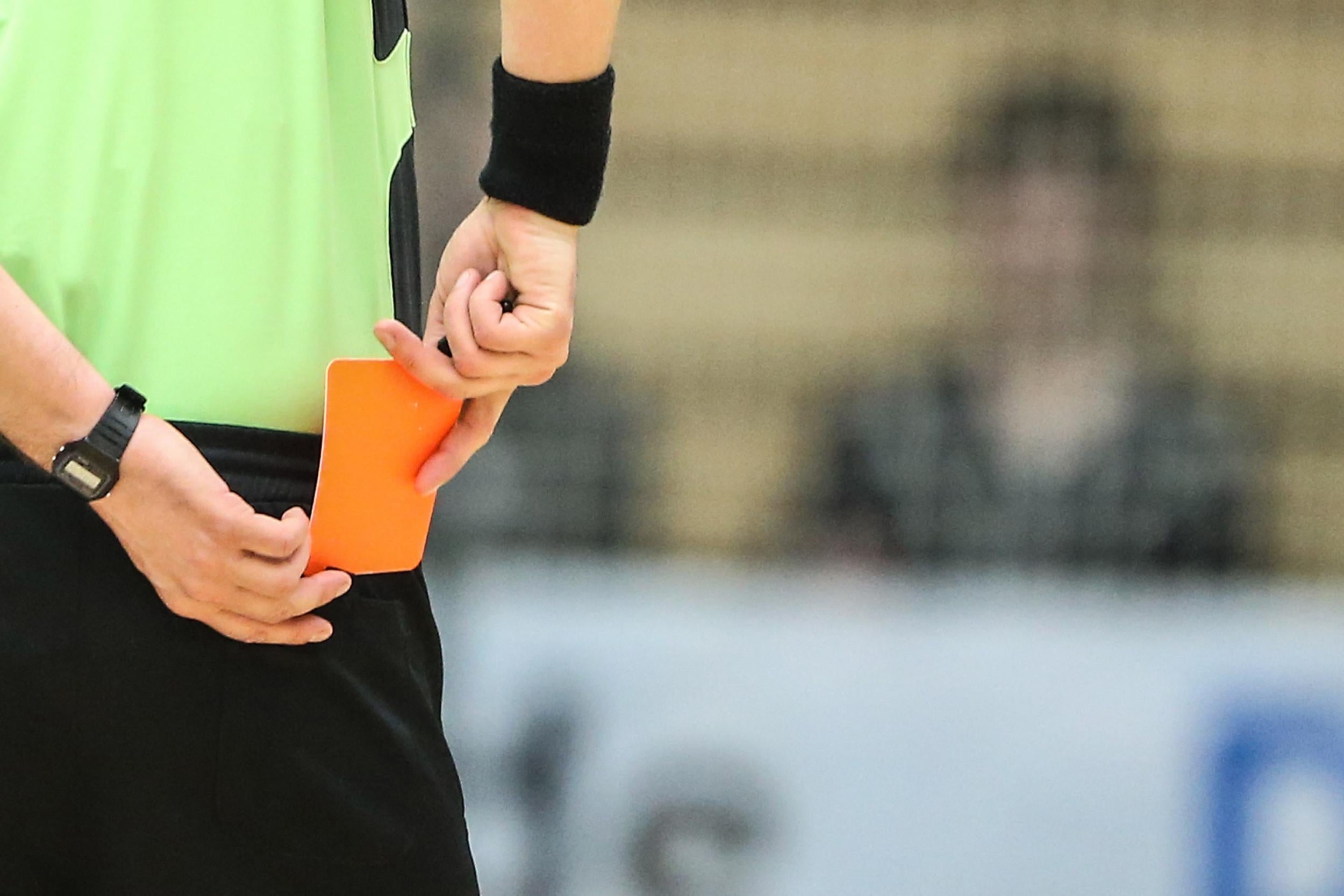 A referee brandishes a red card