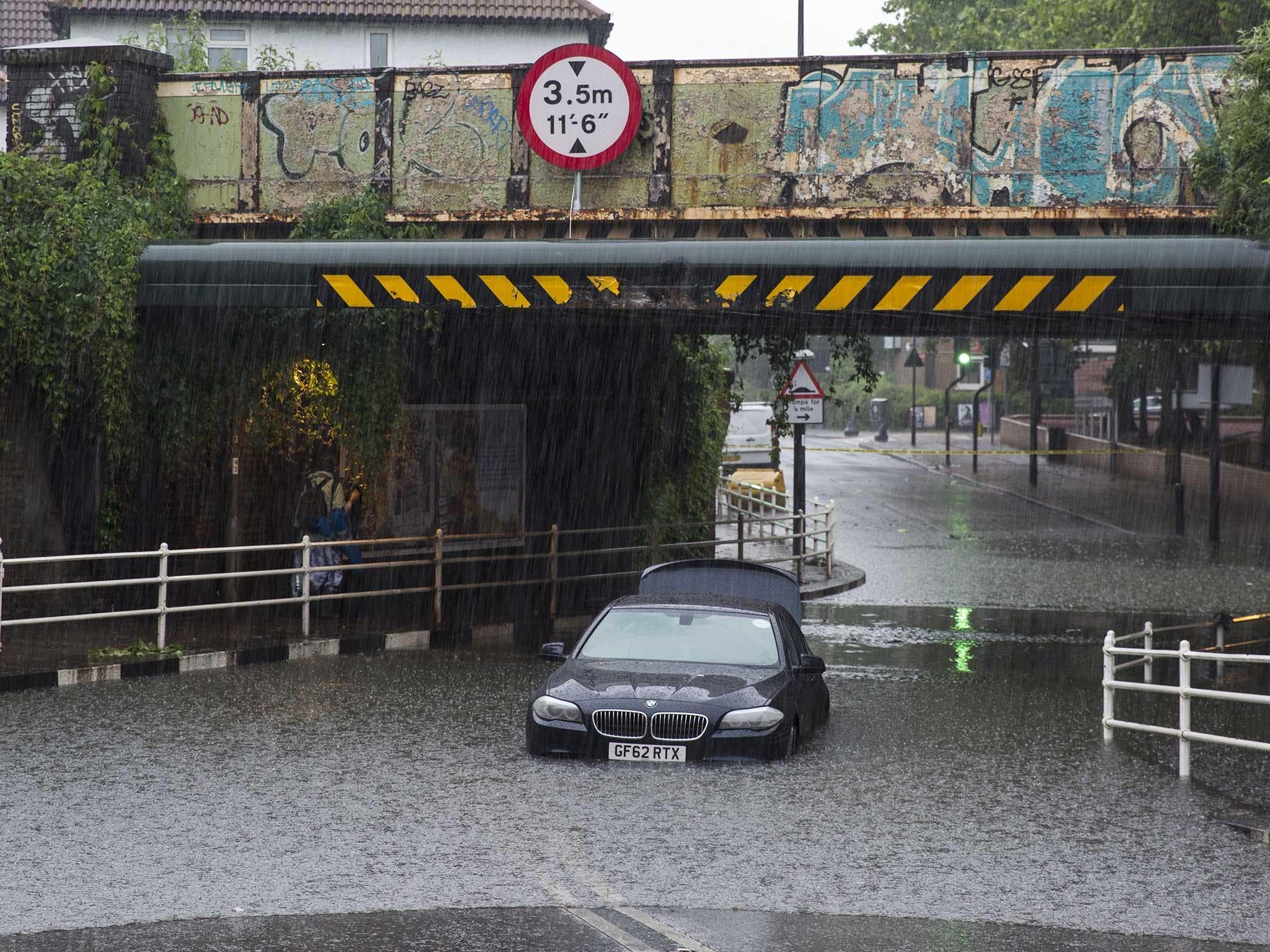 A car is abandoned under a bridge in Battersea after getting stuck in floodwater water