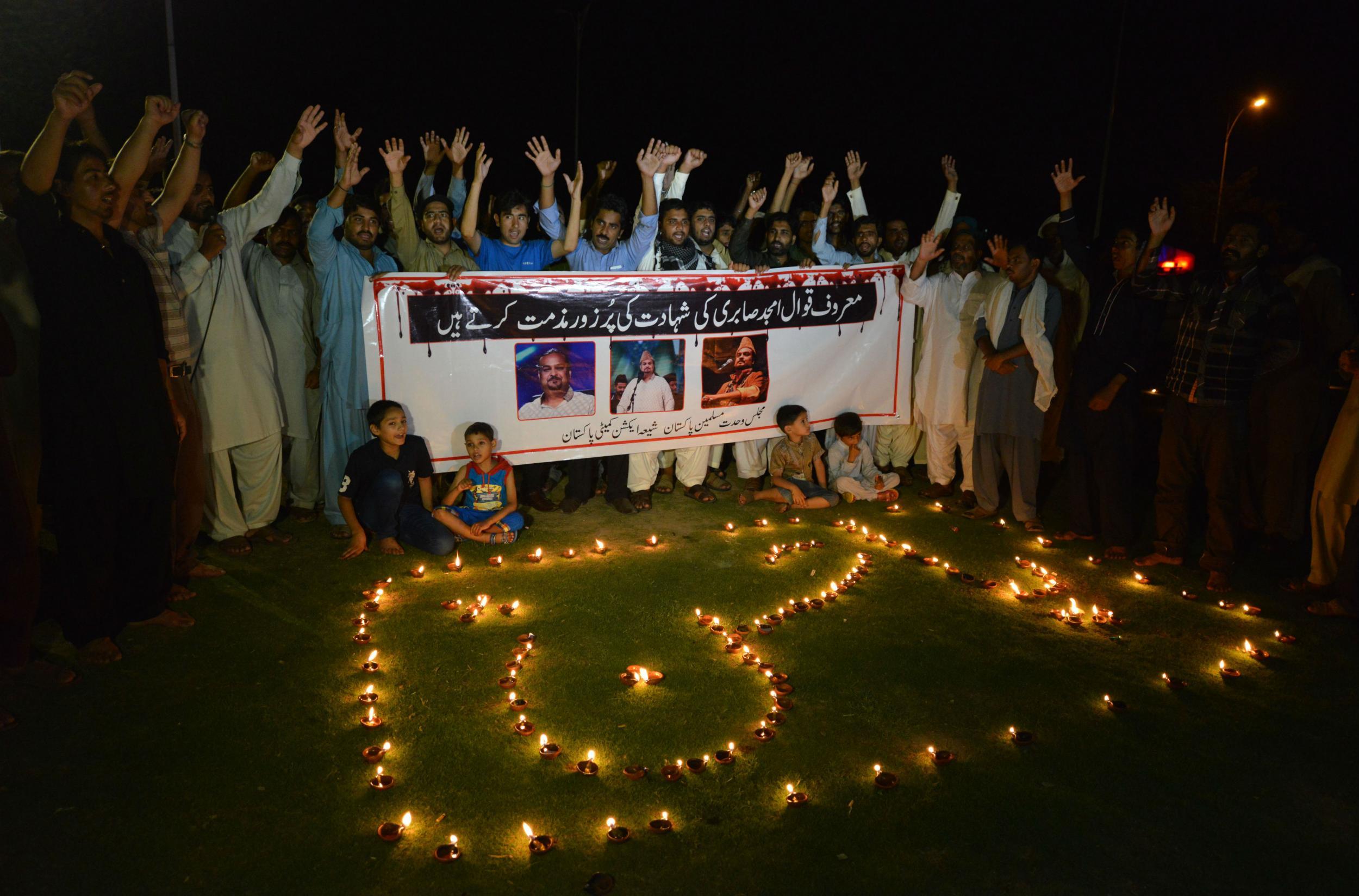 Pakistani Shiite Muslim protesters shout slogans next to oil lamps to pay tribute to Amjad Sabri in Islamabad ( AAMIR QURESHI/AFP/Getty Images)