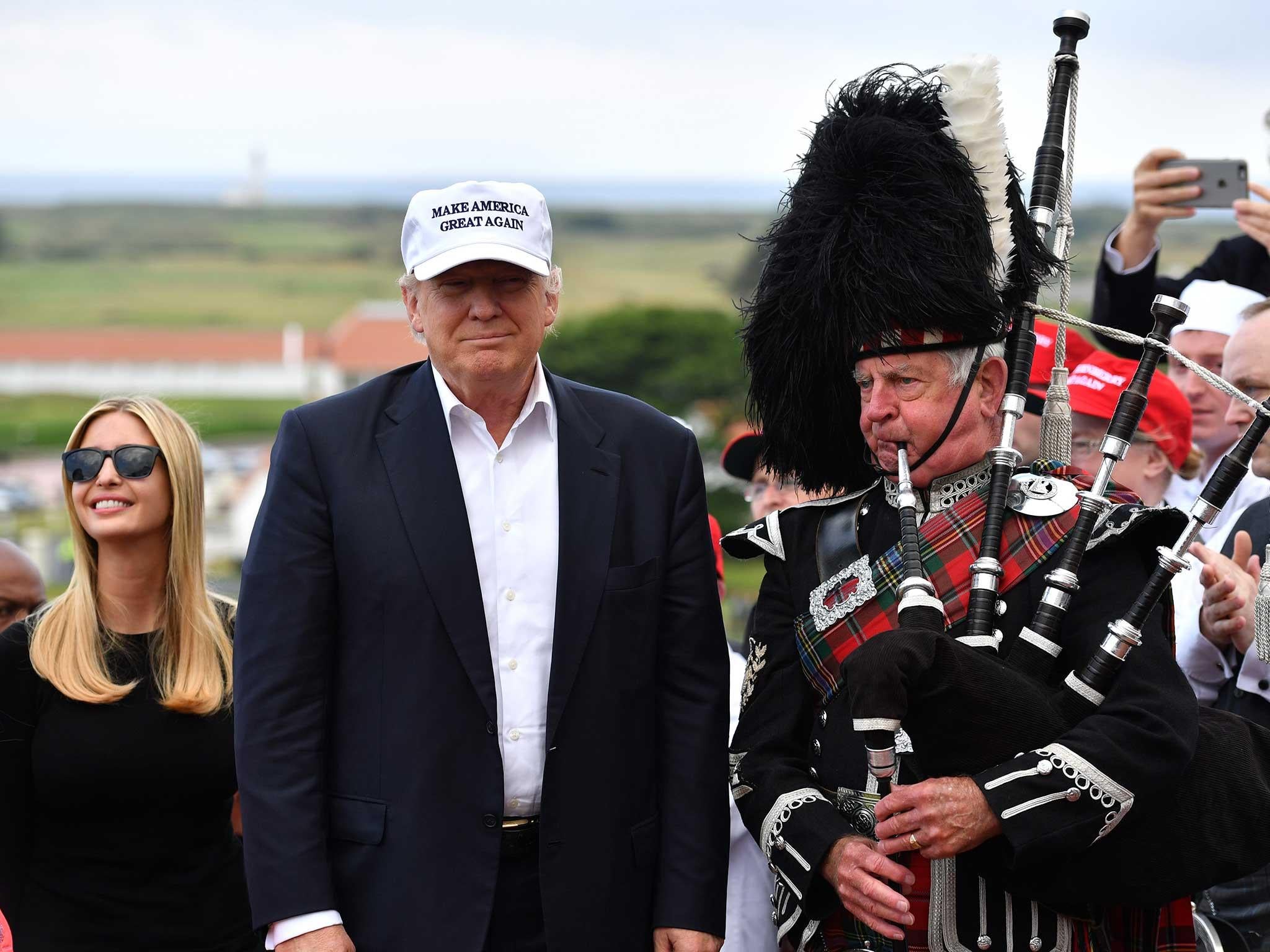 A bagpipe player wears traditional dress next to Donald Trump as they arrive to his resort in Ayr, Scotland