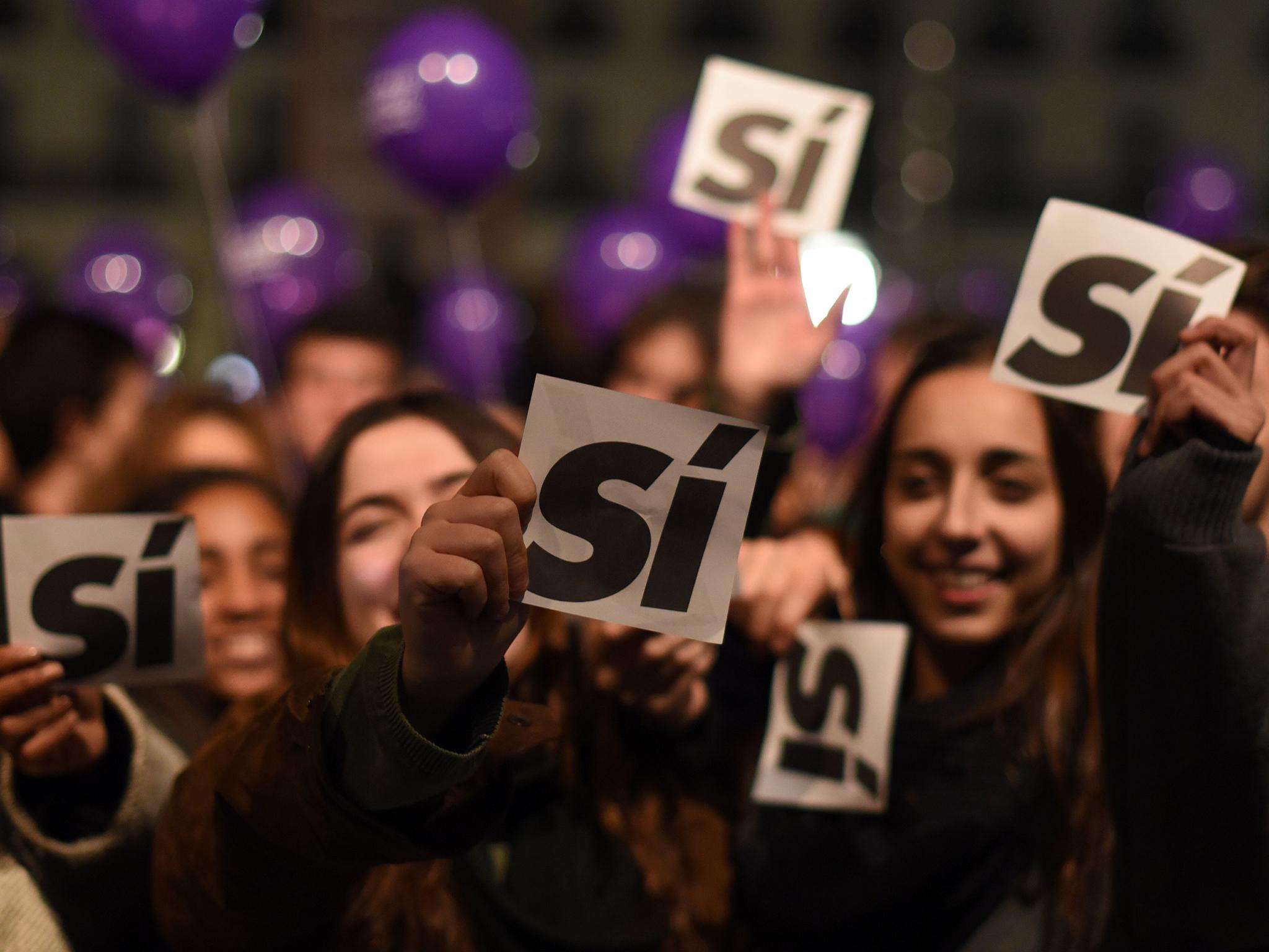 Supporters of left-wing Podemos hold sheets reading 'yes' during previous general election on 20 December