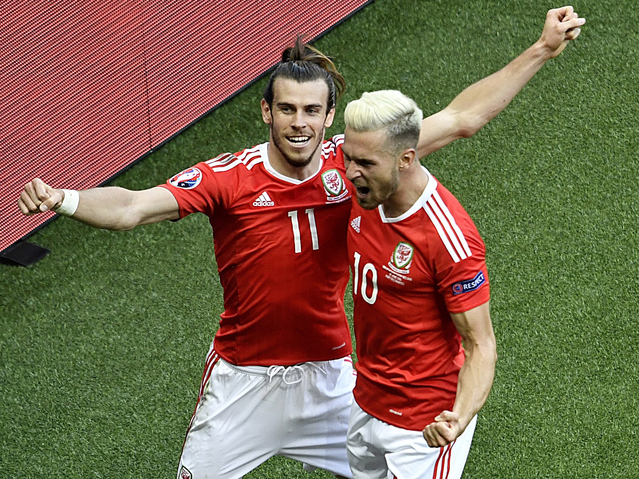 Gareth Bale celebrates with Aaron Ramsey after Gareth McAuley's own goal