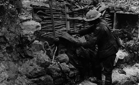 A British soldier covers a dead German on the firestep of a trench near the Somme