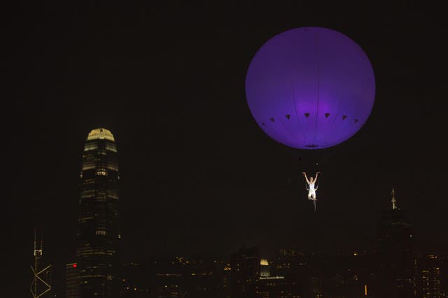A dancer of London's the Dream Engine performs under the heliosphere, a massive helium balloon, with the backdrop of Hong Kong's skyline December 16, 2012