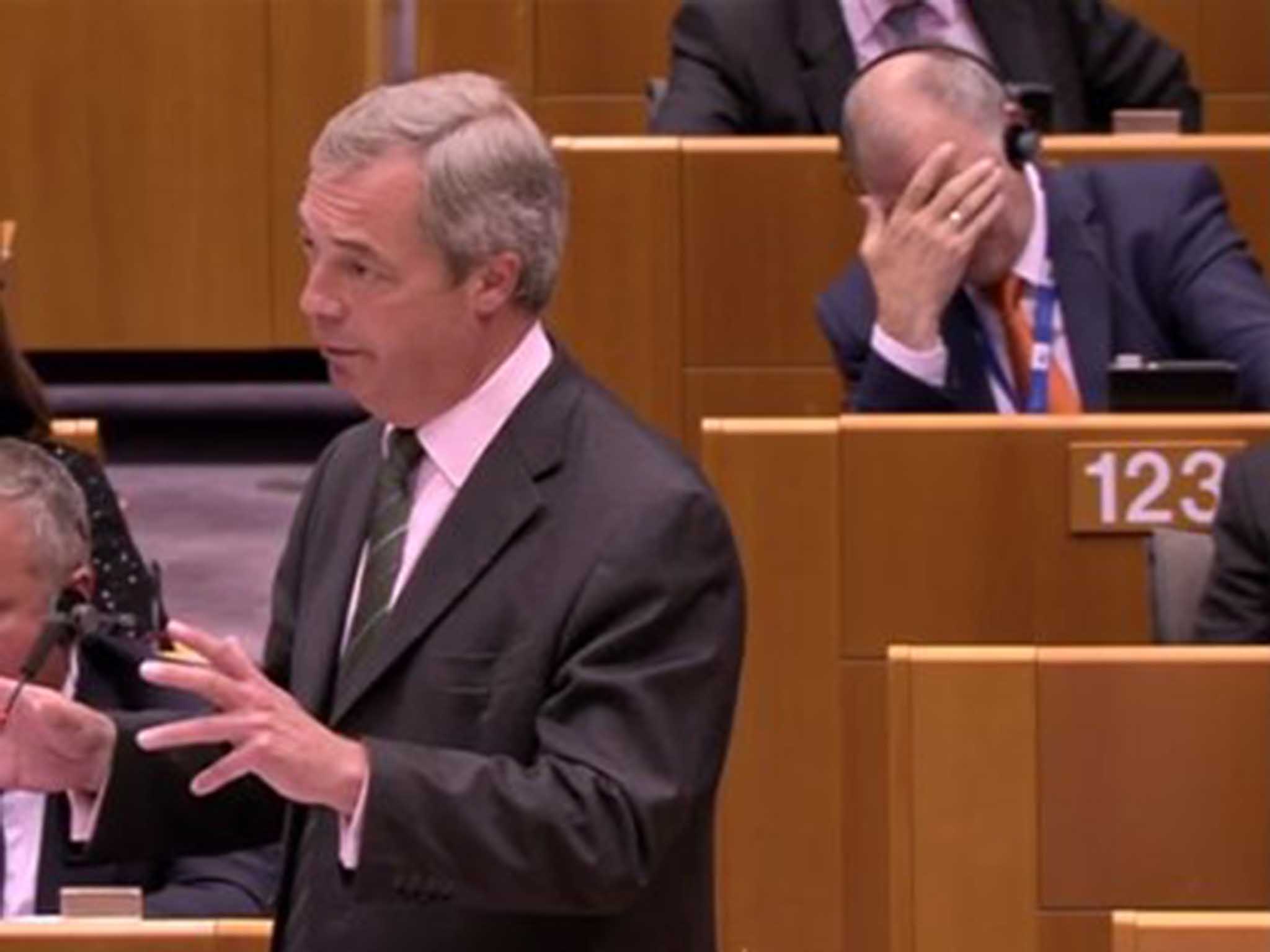 Vytenis Andriukaitis puts his head in his hands as Nigel Farage talks