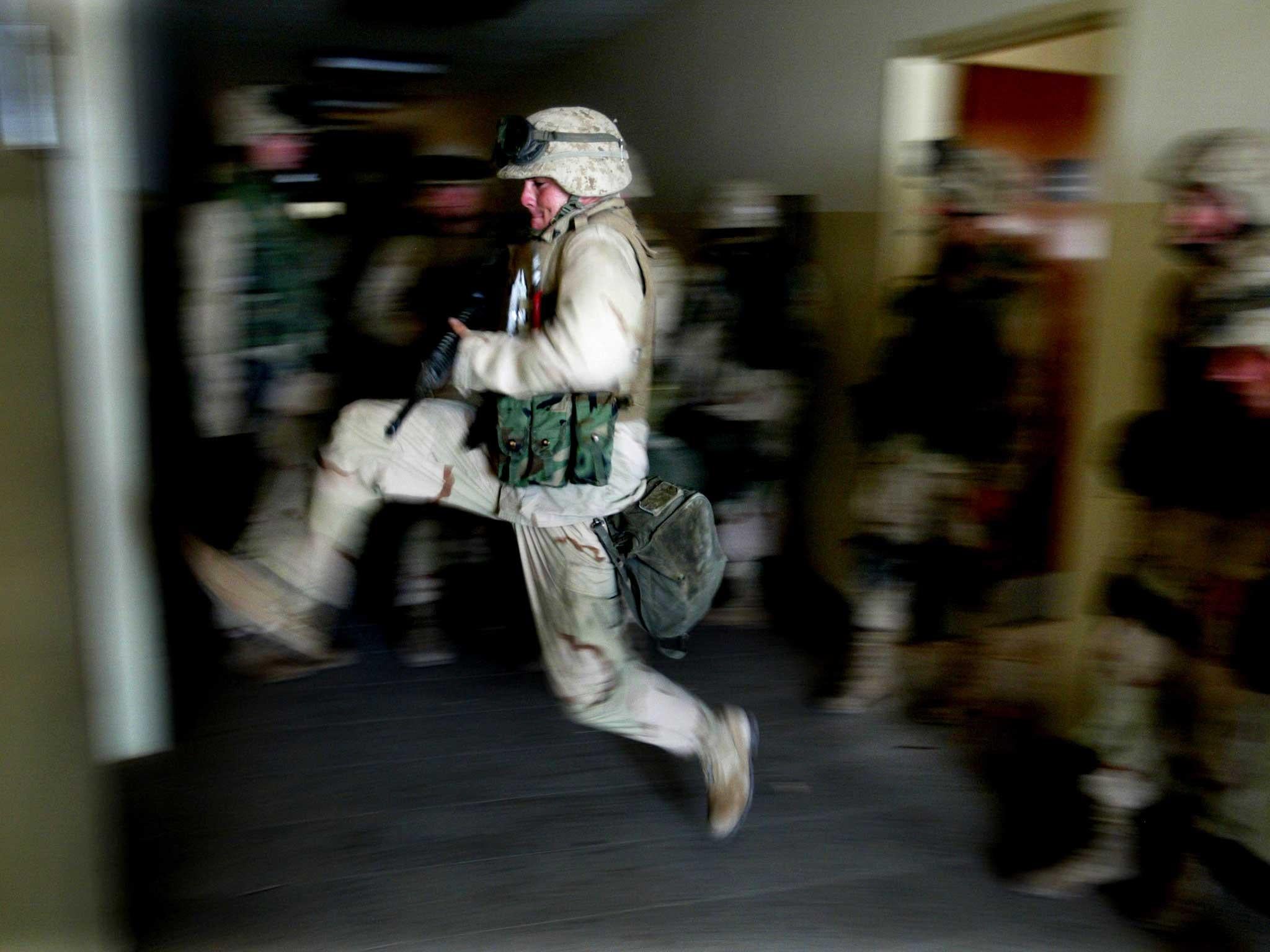 US marines kick in a door while securing a building next to the main hospital, in central Baghdad, which was used as a temporary Iraqi police HQ in 2003