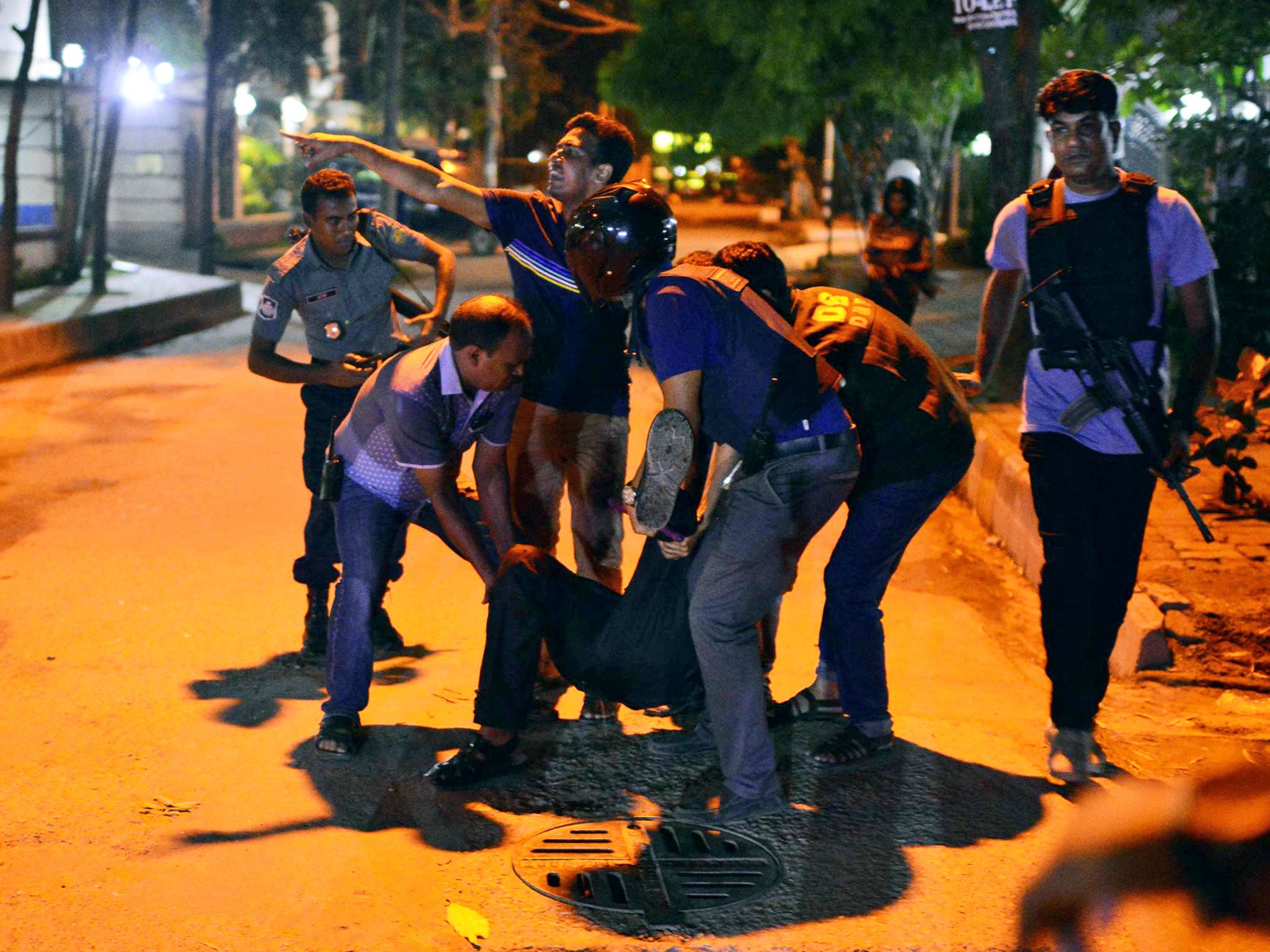 People help an injured person after a group of gunmen attacked a restaurant popular with foreigners in Dhaka, Bangladesh