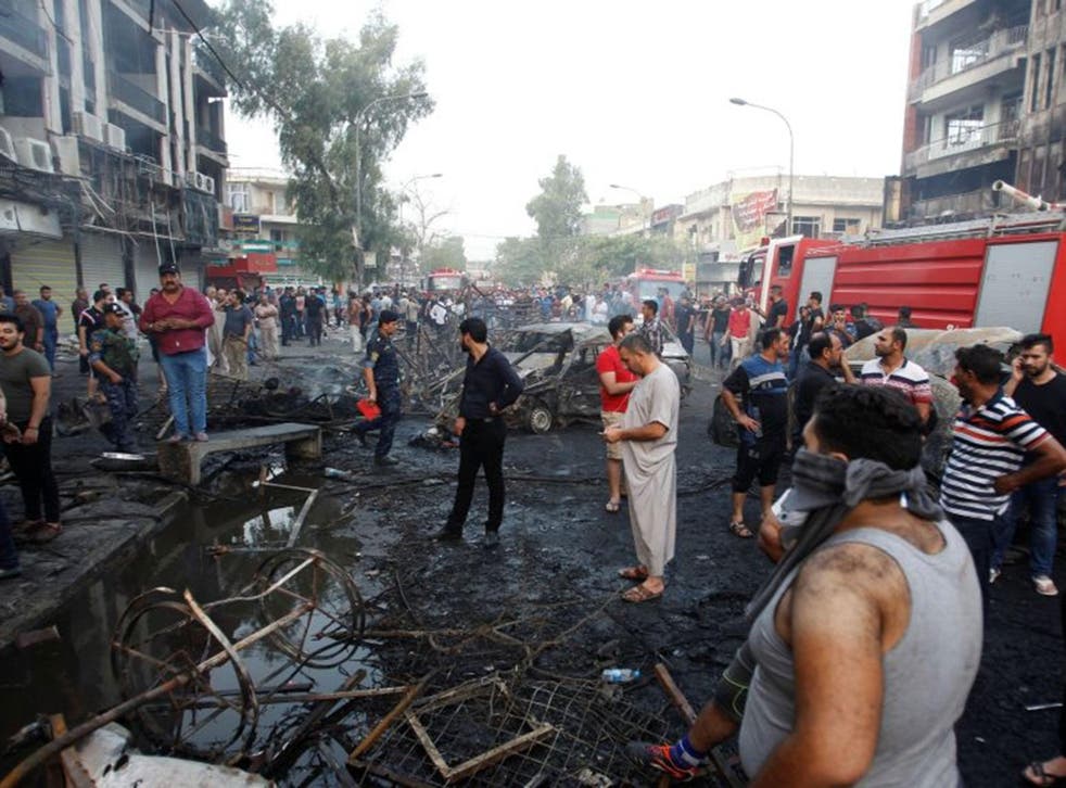 People gather at the site of an Isis suicide car bomb in Baghdad