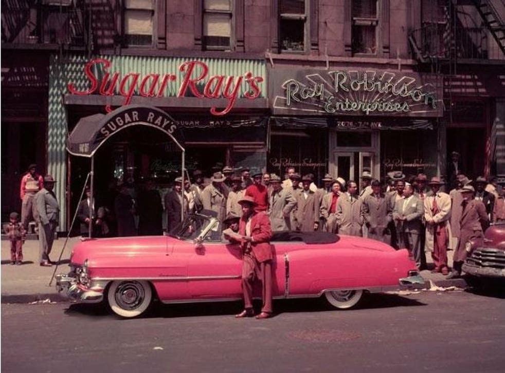 Sugar Ray Robinson enjoys the trappings of his success, stood next to his pink Cadillac and outside his Harlem club