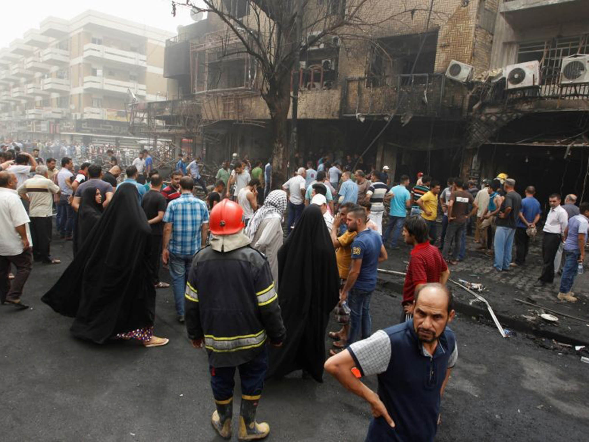 Civilians and security forces stand outside the shopping area where a car bomb exploded