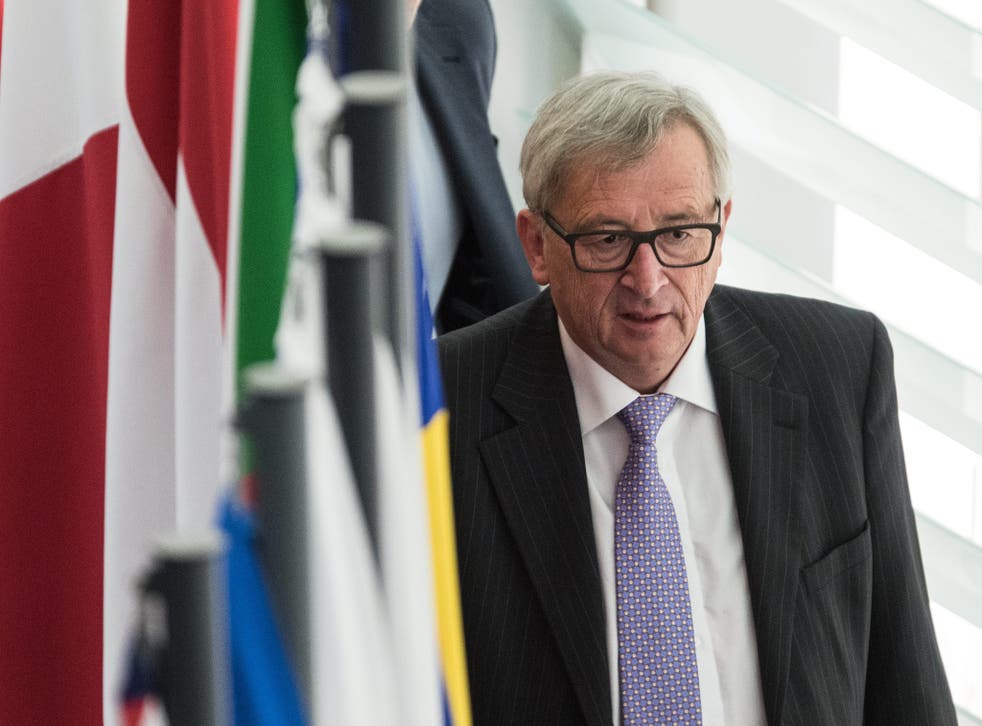 European Commission President Jean-Claude Juncker walks behind flags after a debate in the European Parliament in Strasbourg, France
