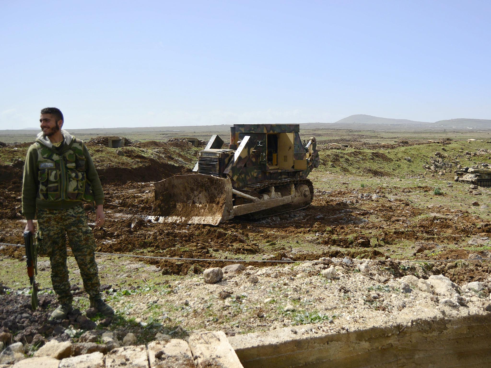 A member of the Syrian government forces stands infront of a bulldozer, north of the southern Syrian city of Deraa