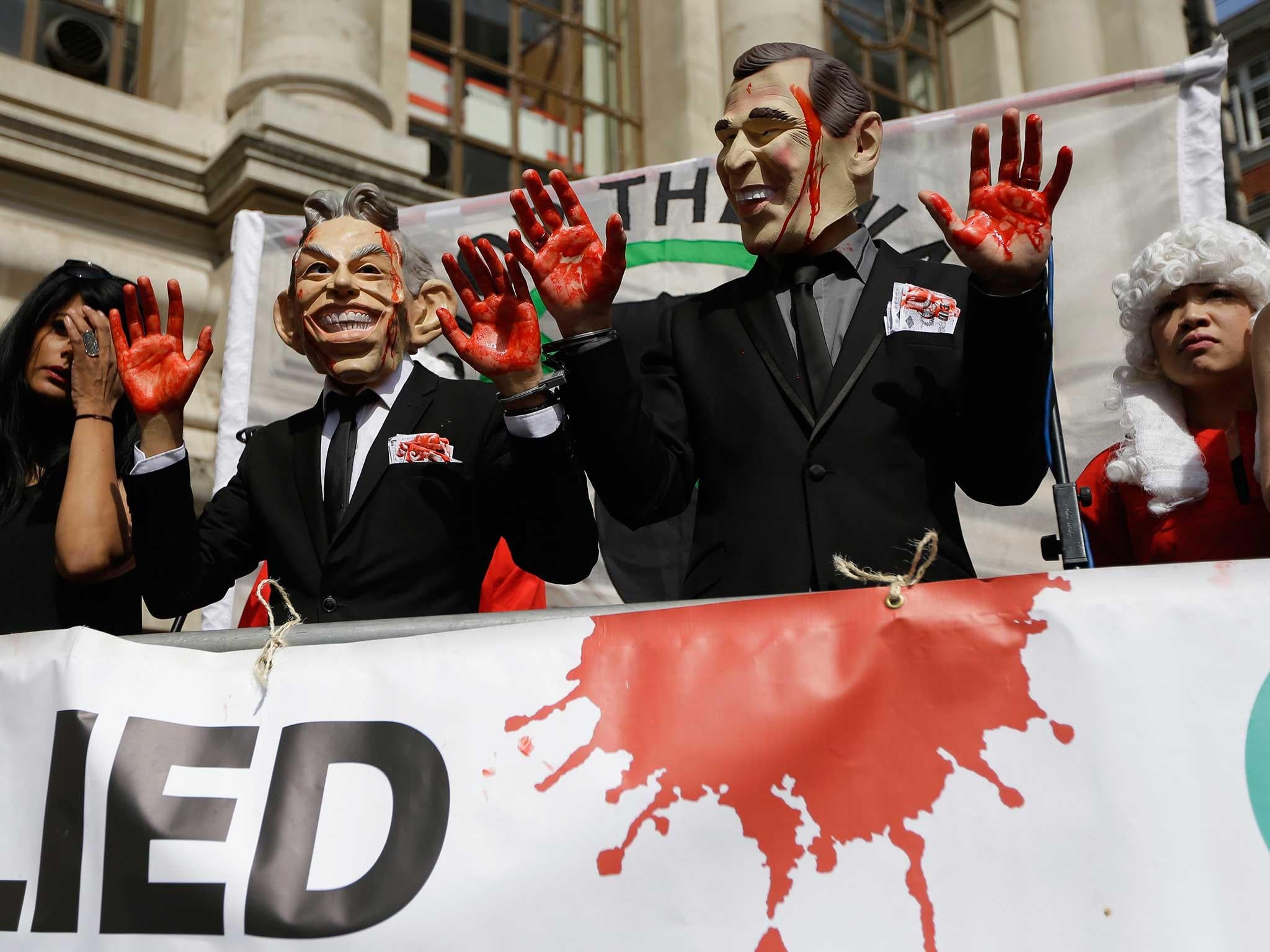 Protesters wearing a former British Prime Minister Tony Blair mask and former U.S. President George W. Bush