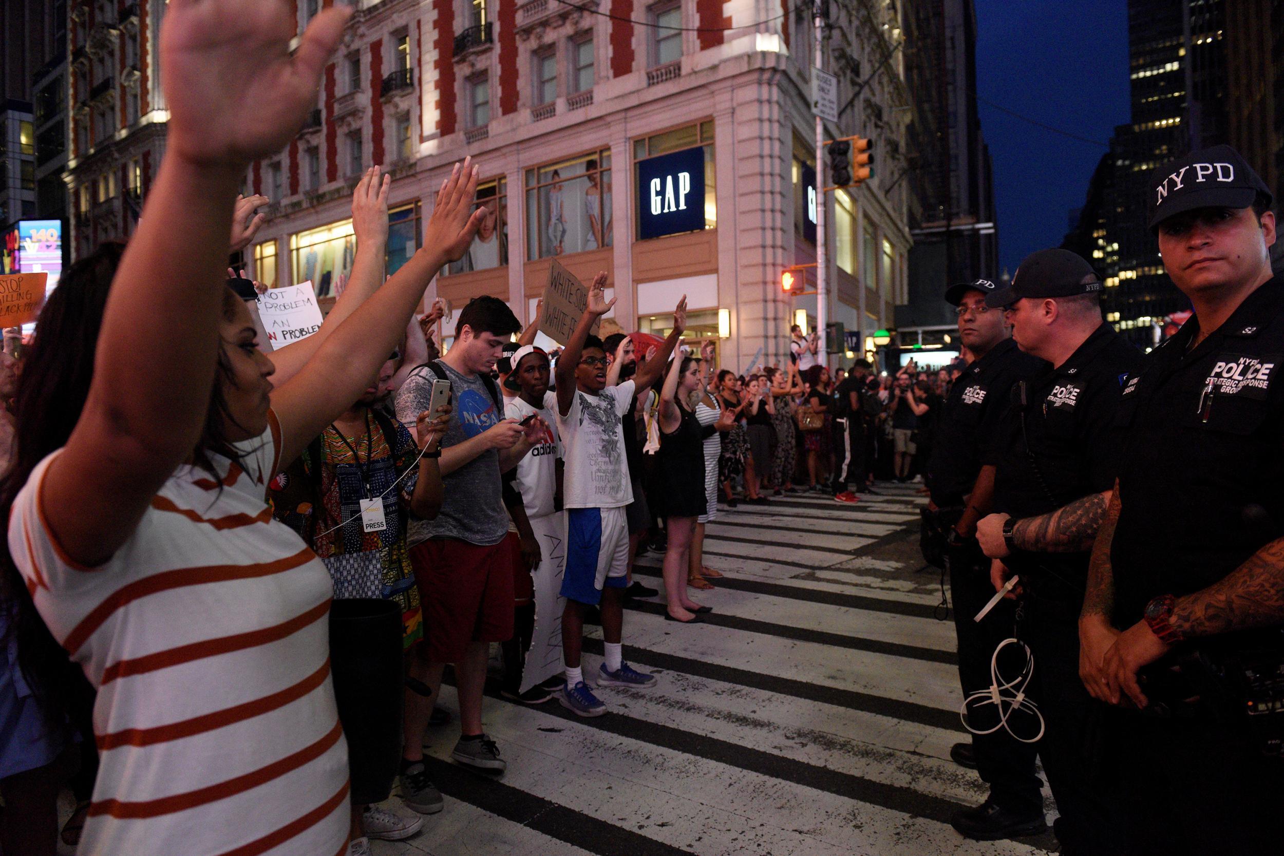 Protesters raise their arms in front of armed US police