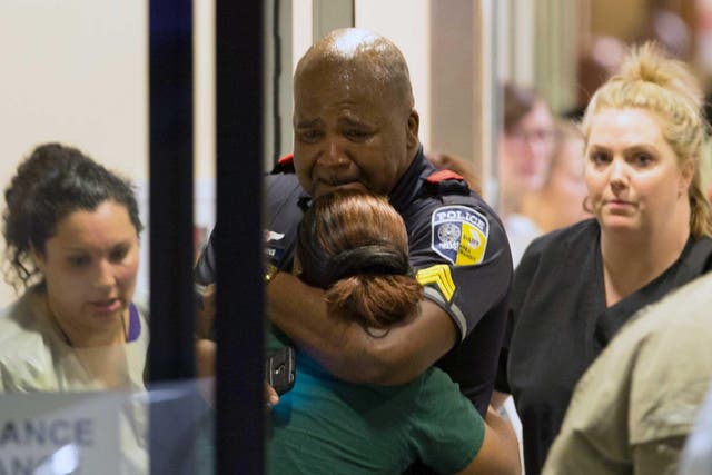 A Dallas police officer is comforted at the Baylor University Hospital after six of his colleagues were shot dead