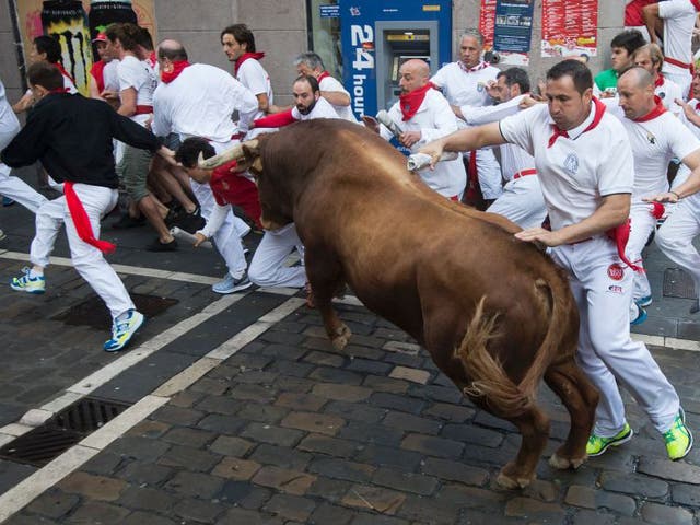 Participants are struck by a Cebada Gago fighting bull on the second day of the San Fermin bull run 2016