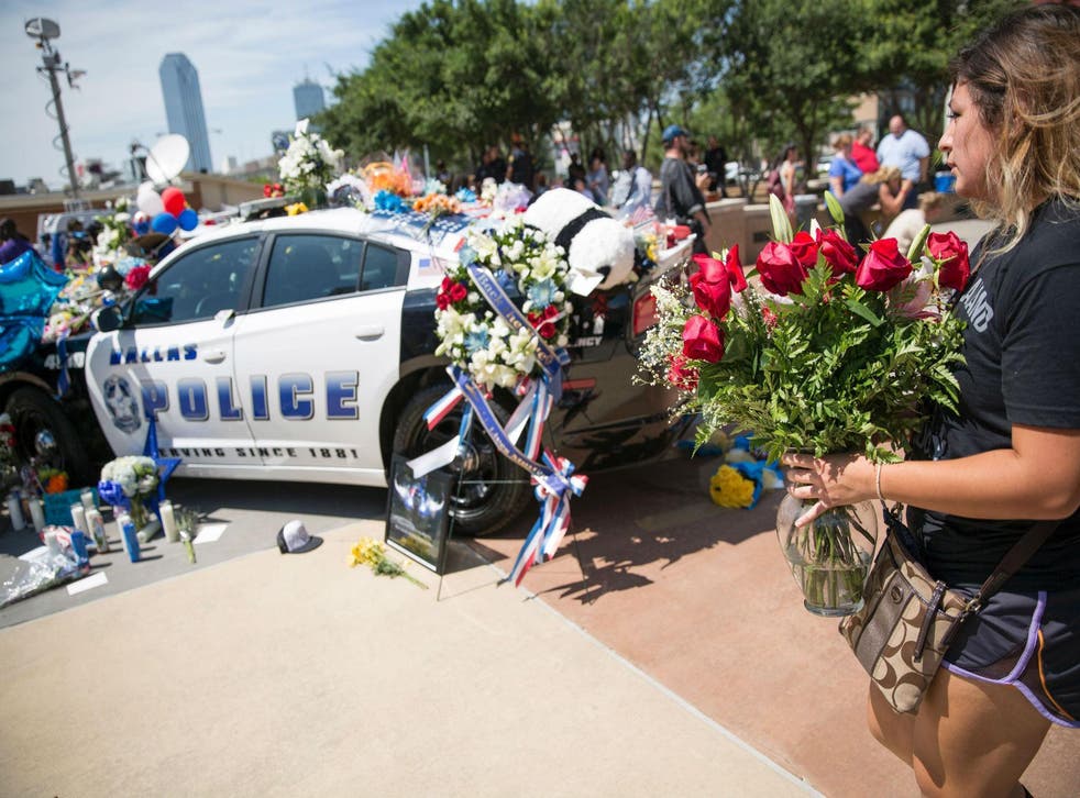 Mourners leave flowers at a patrol car that became a makeshift memorial to the five Dallas police officers killed by a gunman on Thursday night