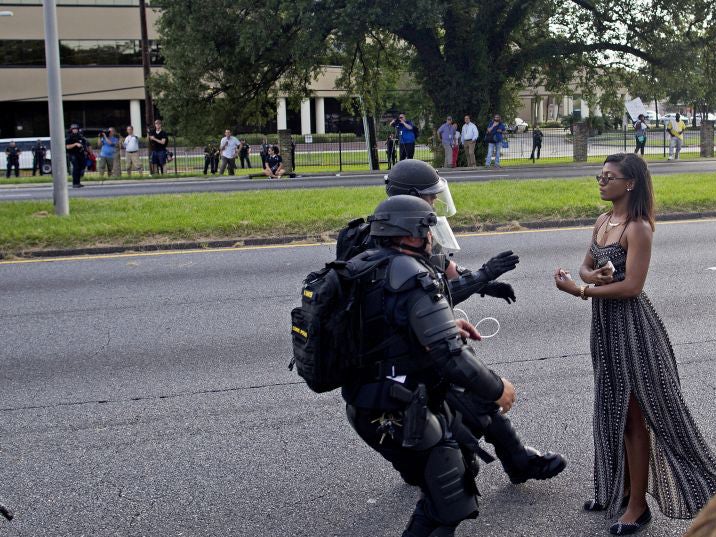 A protester is grabbed by police officers in riot gear after she refused to leave the motor way in front of the the Baton Rouge Police Department Headquarters in Baton Rouge