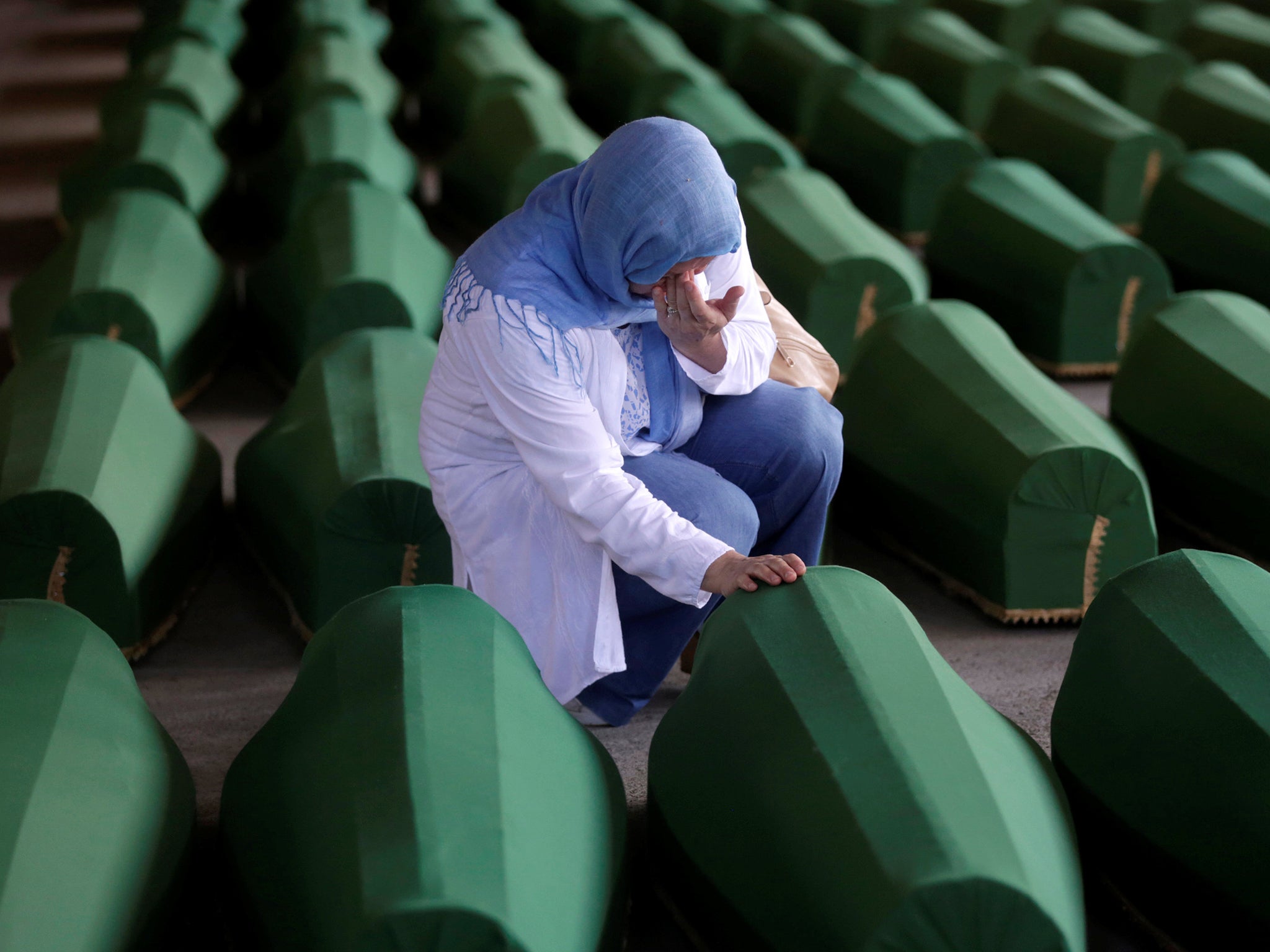 A women weeps next to the remains of 127 victims of the Srebrenica massacre
