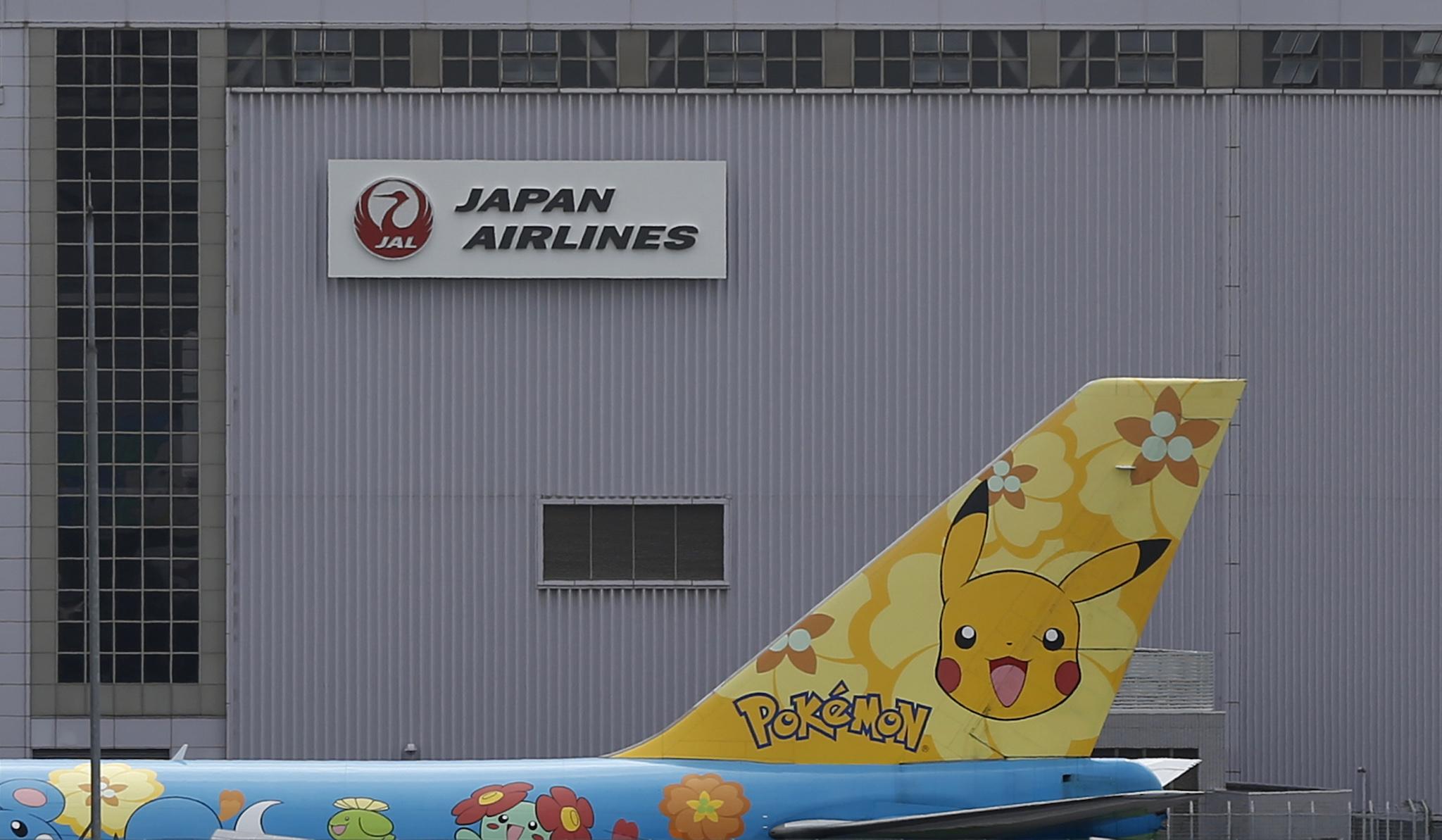 The logo of Japan Airlines (JAL) is seen on a hangar as All Nippon Airways' (ANA) Pokemon Jet moves past it at Haneda airport in Tokyo September 19, 2012